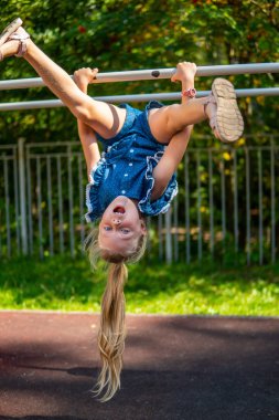 Baş aşağı yeşil orman yakınındaki oyun alanında merdivenlerde ip kız