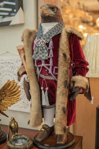 An eagle in a royal mantle in a short fur coat stands on two legs