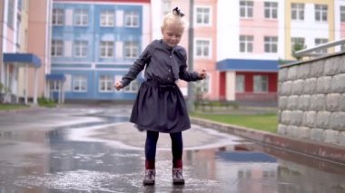 Neşeli çocuk kız bir şemsiye hava berrak sakin olmadan yağmurdan sonra bir su birikintisi yavaş çerçeve atlama