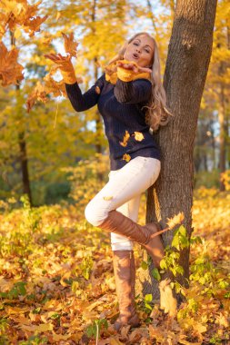 Kız bir ağacın üzerinde dinlenir ve kovboy giysileri, kahverengi çizmeler gün batımında fotoğraflandı