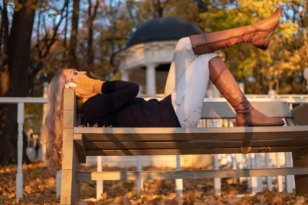 公園のベンチに横たわって電話で話す秋の女の子、散歩の後 — ストック写真