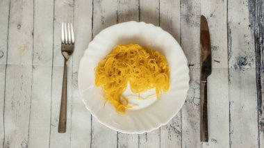 Kötü makarna sunucusu çatalı ve bıçak ahşap masa, çürük makarna, kuru beyaz tabak