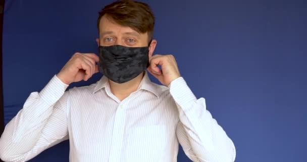 Een volwassen werknemer doet een masker af bloeit achtergrond blauw wit daglicht helder blauw ogen schieten voorste kleding geel — Stockvideo