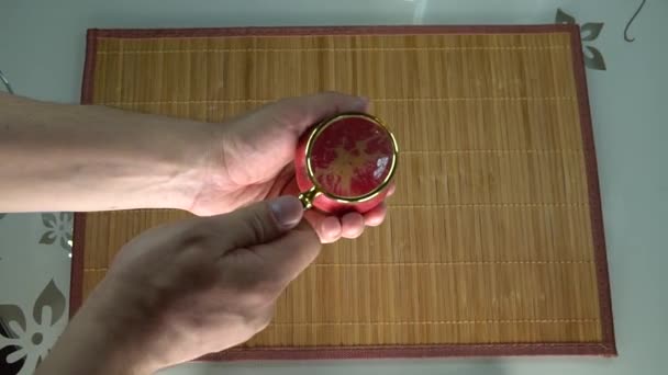 Look at the apple through a magnifying glass studying the object on a brown background using your hands to analyze — Stock Video