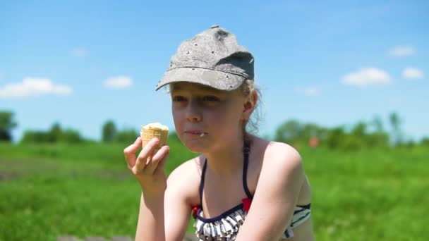 Красивая девушка ест мороженое в природе, голубое небо с белыми облаками, зеленая трава, Счастливый с удовольствием ест — стоковое видео