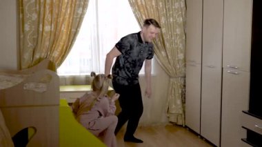 Şen şakrak eski bir oyun, neşe dolu yerli bir bebekle birlikte şık elbiseli parlak bir odada yatağı hareket ettir. Güneşli bir pencereye karşı.