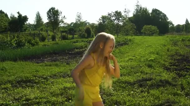 Vrolijke glimlacht naar de camera springen en strekken zijn haar, op zoek vrolijk om te genieten van het concept tegen de achtergrond van groen gras en blauwe lucht op het veld. Zomer in de natuur — Stockvideo