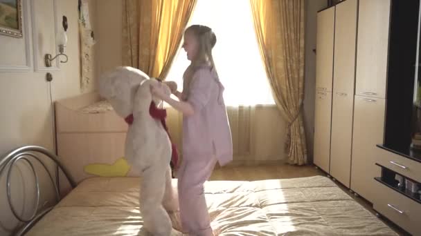 Das Mädchen spielt mit Teddybär, lächelt und springt gern mit ihm und lacht. — Stockvideo