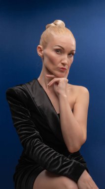 Kutsanmış genç bir kadın bir sandalyede oturuyor, eşsiz bir smokin içinde, mor beyaz gün ışığında Avrupalı bir yüzü olan bir kadın. Yüzsüzlükler