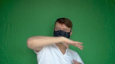 Mutlu koca adam maskesini çıkartıyor ve beyaz tenli, arka planı yeşil beyaz gün ışığıyla dans ediyor.