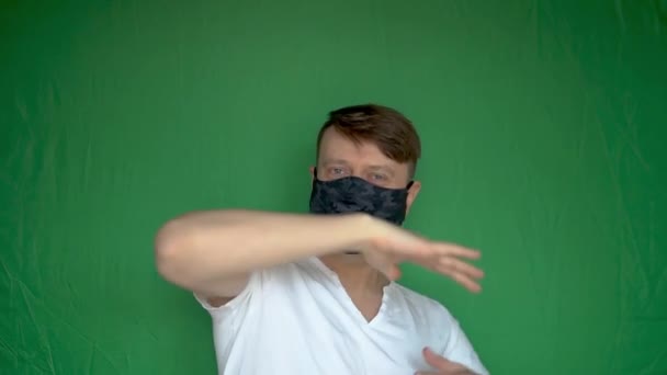 Happy big man takes off the mask from the face dancing and with white skin, background green white daylight — Stock video