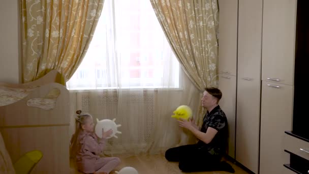Il goditore gioca palle guanto con un bel bambino nativo nella stanza dei bambini in abiti da casa. Contro la culla e il divano. — Video Stock
