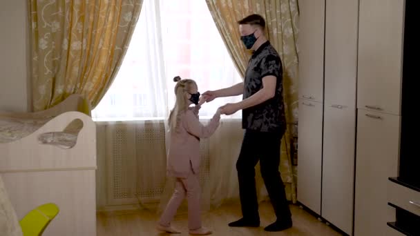 Gelukkige oude vader danst met een vrolijk meisje een aansteker in een kinderkamer in huiskleding. Tegen de wieg en de bank. Ze zijn gemaskerd. — Stockvideo