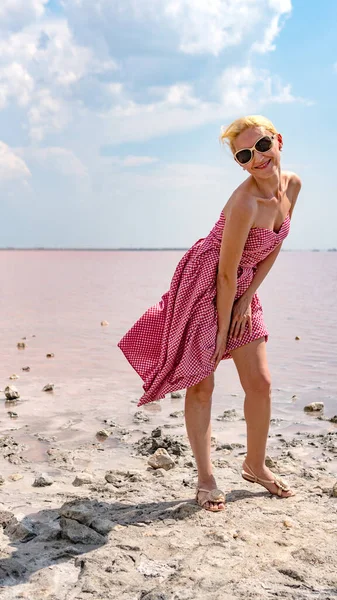 Chica en rojo en un lago salado hermosa tarde, en el calor del verano sopla un fuerte viento, una chica en gafas de sol —  Fotos de Stock