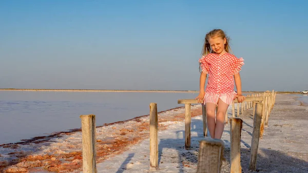 Salt Lake siede una ragazza su un bastone di legno con una gonna rossa e sorride — Foto Stock