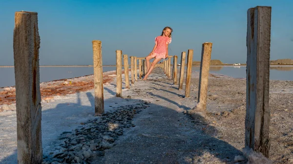 Salt Lake, la ragazza seduta a piedi nudi in abito rosso su bastoni di legno, meditato — Foto Stock