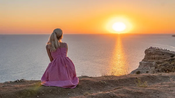 Ragazza allegra con un aspetto caucasico guarda il tramonto si erge al volto del sole la sera d'estate — Foto Stock