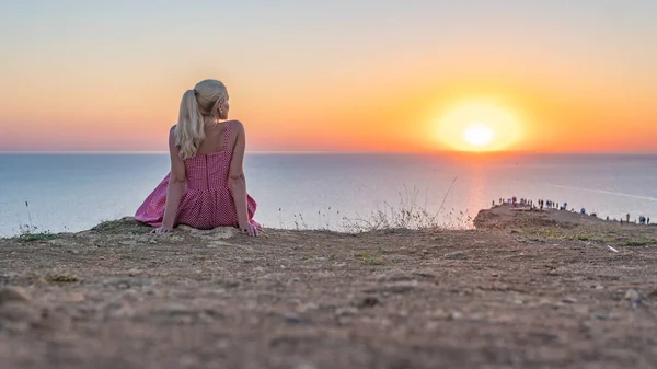 Una giovane ragazza guarda il tramonto si erge al volto del sole la sera d'estate — Foto Stock
