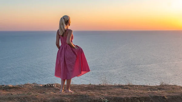 Sorridente ragazza adulta con un bellissimo aspetto guarda il tramonto con la schiena in estate la sera — Foto Stock