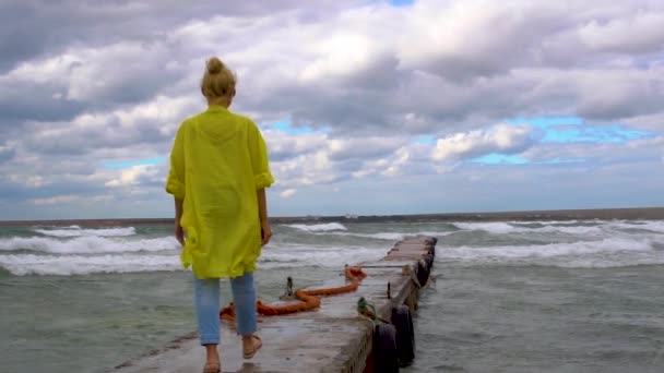 Sjöflicka på piren i dåligt väder, storm i gula kläder starkt slå våg, på sommaren — Stockvideo