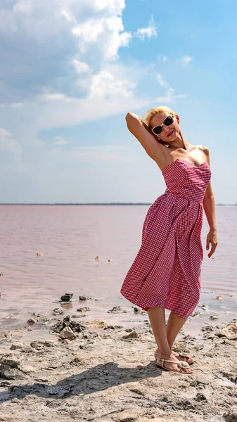 Dama en un hermoso vestido joven con labios tiernos sobre el fondo de un lago rojo nubes azules en el clima cálido y soleado —  Fotos de Stock