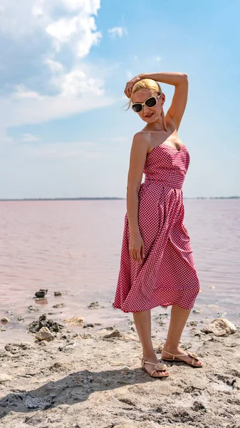 Felice in un abito rosso giovane sullo sfondo di un lago salato nel pomeriggio e in estate — Foto Stock