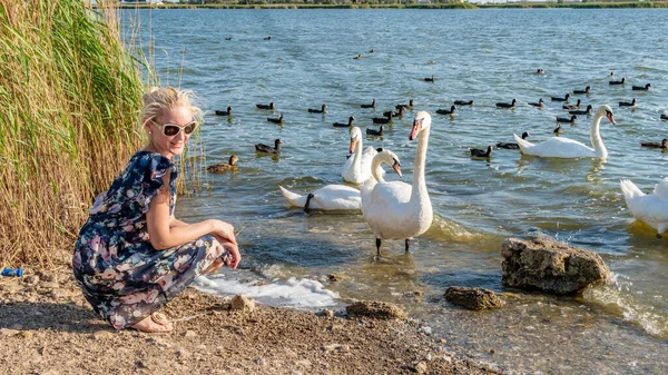 Donna sorridente in un bellissimo vestito adulto con bellissimi occhi sullo sfondo di uccelli cigni sul lago in una giornata estiva — Foto Stock
