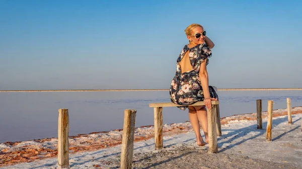 Giovane donna sorridente in un bel vestito con labbra dolci su uno sfondo salato come l'inverno su un lago con nuvole blu nel caldo sole — Foto Stock