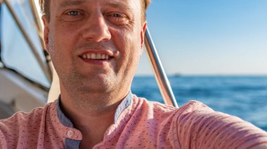 Yattaki adam, neşeli, denizin ufkunda gülümseyen, kırmızı gömlekli mutlu bir yaz tatili.