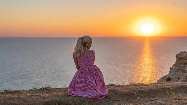 Una giovane donna dall'aspetto eccellente guarda il tramonto con le spalle in estate la sera — Foto Stock