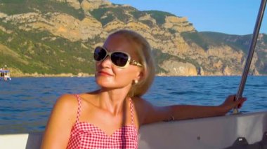 Güzel bir teknede dinlenmek, denizin etrafında narin dudakları olan bir yetişkin, güneş gözlüklerindeki giysi aktiviteleri konsepti güzel ufuk çizgisi.