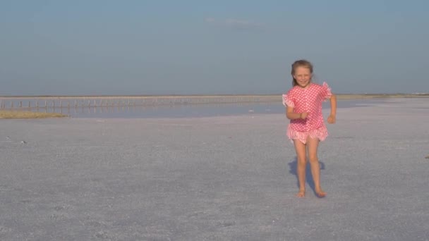 Bonne fille court à notre réunion, sur le sel blanc, le lac salé rose, dans la Crimée. Dans une robe rouge pieds nus — Video