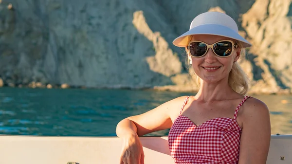 Ragazza felice che riposa su uno yacht, un adulto guarda la macchina fotografica intorno al mare, in occhiali da sole in estate — Foto Stock