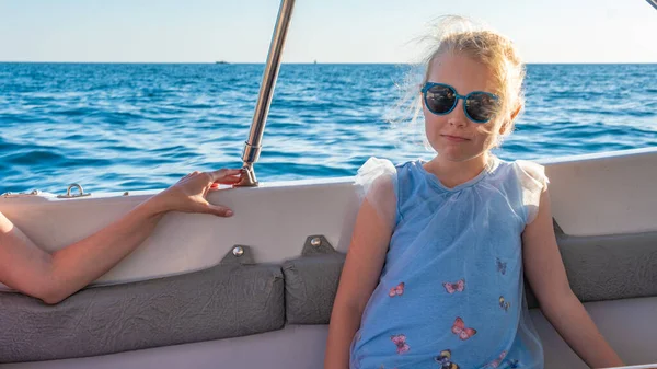 Hermosa chica sentada en un barco, una joven sonriendo a la cámara contra el telón de fondo del mar, el concepto de bienestar gafas monocromáticas, tiempo soleado —  Fotos de Stock