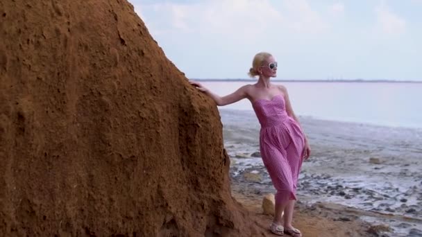 Hermosa dama en un vestido rojo joven sonriendo en el fondo de un lago de sal durante el día y el verano — Vídeo de stock