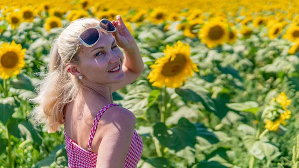 in sunflowers in a red checkered dress in sunglasses, a beautiful blonde in the heat of summer the sun is shining Light-haired