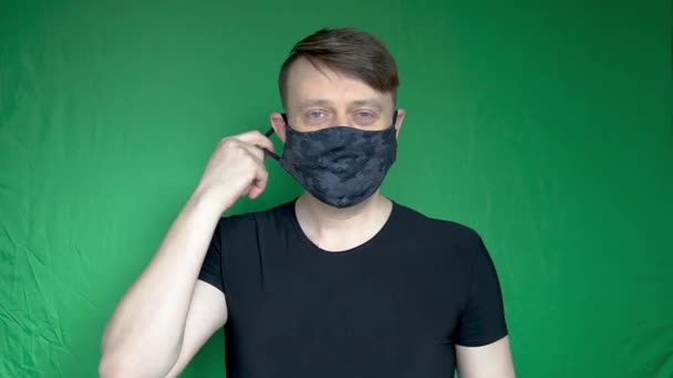 Úspěšný unavený muž si sundá masku z hlavy a baví se krásným vzhledem na zeleném pozadí bílého denního světla — Stock video