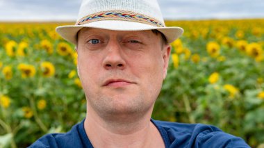 Yazın elinde ayçiçekleri olan şapkalı adam.