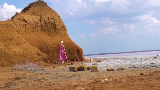 Feliz en un vestido rojo joven en el fondo de un lago de sal durante el día y en verano — Vídeos de Stock