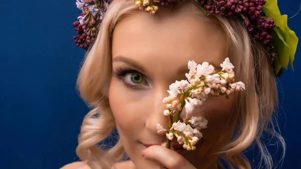 Leylak rengi bir çelengin içinde sarhoş bir genç gün ışığıyla mavi bir arka planda eğleniyor.