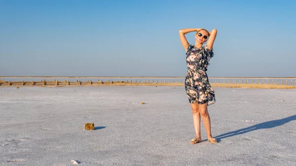 Ragazza allegra in un bel vestito giovane sullo sfondo di un lago bianco di sale nel caldo tempo soleggiato — Foto Stock