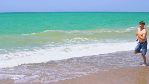 Blanke man loopt langs het strand langs de zee in de zomer bij zonnig weer — Stockvideo