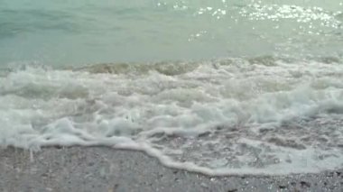 Deniz sörfü, güzel dalgalar, çakıl taşlı plaj ritmi. Yavaşça parlayan su