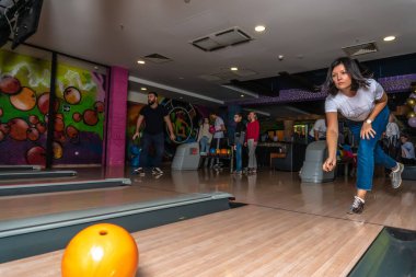 Güzel esmer kız bovling oynuyor, sarı bir top atıyor, oyun kulübü sezonunda. RUSSIA, MOSCOW - SEP 20, 2020