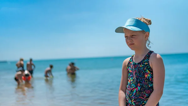 Una chica en el mar en una gorra descansa en el fondo de la gente cielo claro en un traje de baño —  Fotos de Stock