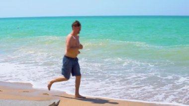 Adam şortlu, kalın beyaz dalgalarda koşuyor.