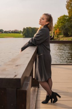 Neşe dolu genç Stoi, karizmatik bir görünüşü olan ve sonbaharda iskelede güzel bir ceketi olan deniz kenarında.