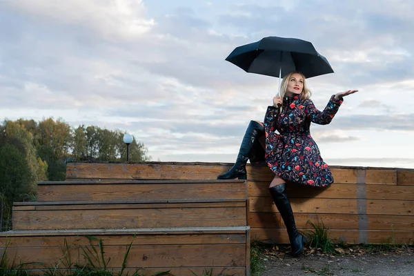 Una ragazza con un ombrello nero siede sulle scale un sacco di cielo blu — Foto Stock