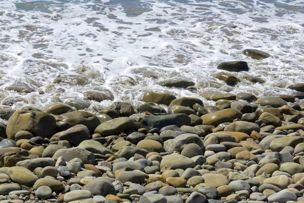 ビーチの靴屋と石と白い泡の 青い波に洗われて自然の背景 — ストック写真