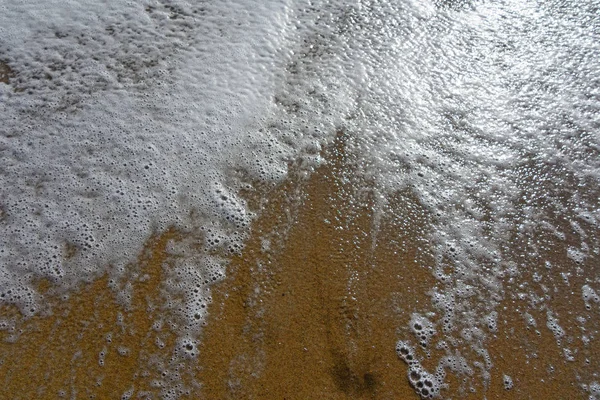 黄色の砂の上に輝く海波の泡のような石鹸します — ストック写真